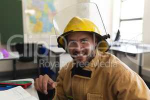Front view of happy male firefighter with helmet in classroom