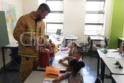 Side view of male Caucasian  firefighter teaching schoolkids about fire safety in classroom