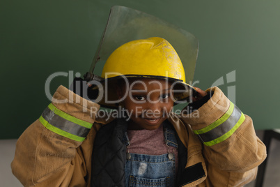 Front view of black schoolgirl with fire uniform looking at camera in classroom