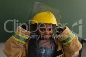 Front view of black schoolgirl with fire uniform looking at camera in classroom