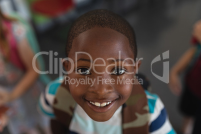 Close-up happy schoolboy with schoolbag looking at camera in classroom