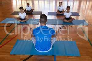 Yoga teacher teaching yoga to school kids in school