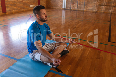 Yoga teacher doing yoga and meditating on a yoga mat in school