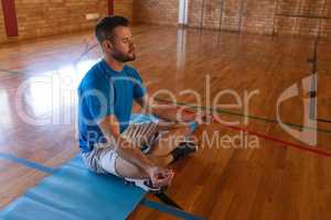 Yoga teacher doing yoga and meditating on a yoga mat in school