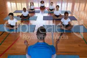 Yoga teacher teaching yoga to school kids in school