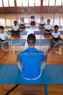 Yoga teacher teaching yoga to school kids in school