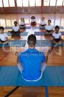 Yoga teacher teaching yoga to school kids in school