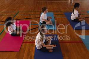 Schoolkids doing yoga and meditating on a yoga mat in school