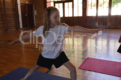 Schoolgirl doing yoga on a yoga mat in school