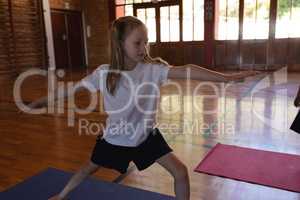 Schoolgirl doing yoga on a yoga mat in school