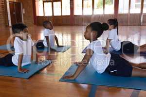 Schoolkids doing yoga on a yoga mat in school