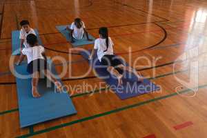 Schoolkids doing yoga on a yoga mat in school