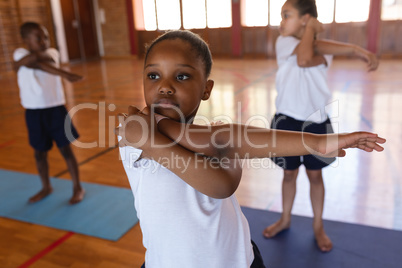 Schoolgirl doing yoga on a yoga mat in school