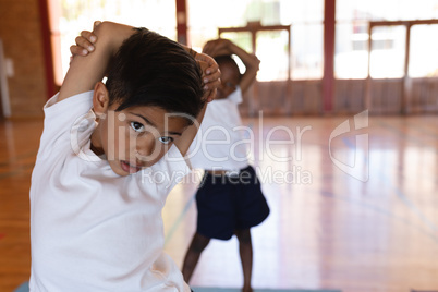 Schoolboy doing yoga on a yoga mat in school
