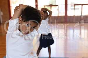 Schoolboy doing yoga on a yoga mat in school