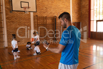 Basketball coach using digital tablet at basketball court in school