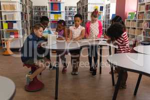 Group of schoolkids studying together at table in school library