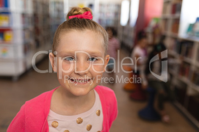 Happy cute schoolgirl looking ta camera in school library