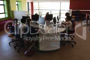 Group of schoolkids studying on desktop pc in school