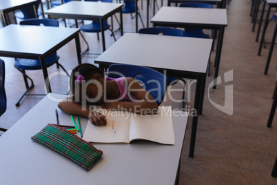Schoolgirl sleeping at desk in classroom