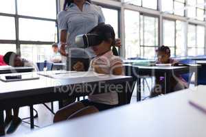 School girl using virtual reality headset at desk in classroom