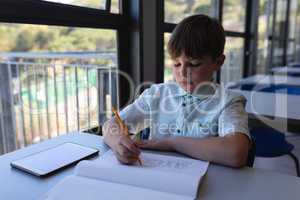 Schoolboy drawing on notebook at desk in classroom