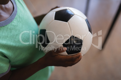 Schoolboy holding football in classroom