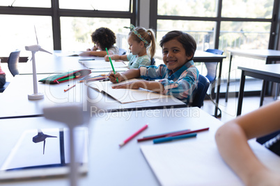 Schoolboy sitting at desk and looking at camera in classroom