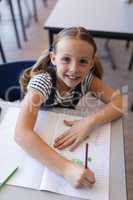 Schoolgirl looking at camera at desk in classroom