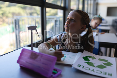 Schoolgirl looking up at desk in classroom