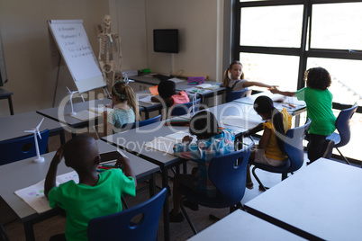 Schoolkids studying at desk in classroom