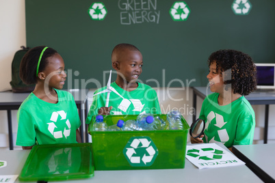 Schoolkids studying about green energy and recycle at desk in classroom