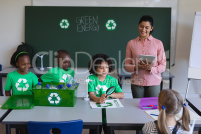 Schoolkids studying about green energy and recycle at desk in classroom