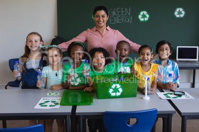 Happy schoolkids and teacher looking at camera in classroom