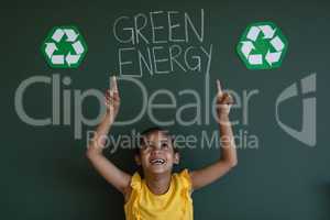 Smiling schoolgirl with arms up standing against green energy board in classroom