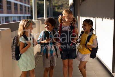 Schoolkids with schoolbags talking with each other in hallway