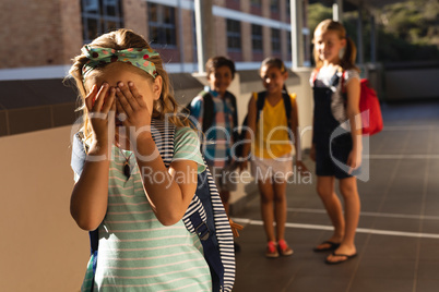 School friends bullying a crying girl in hallway of elementary school