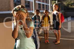 School friends bullying a crying girl in hallway of elementary school