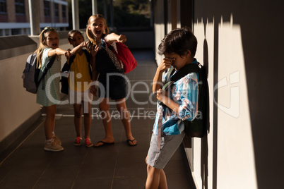 School friends bullying a crying boy in hallway of elementary school