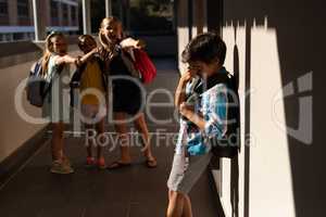 School friends bullying a crying boy in hallway of elementary school