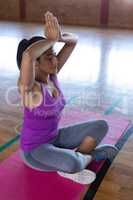 Female yoga teacher doing yoga and meditating on a yoga mat in school