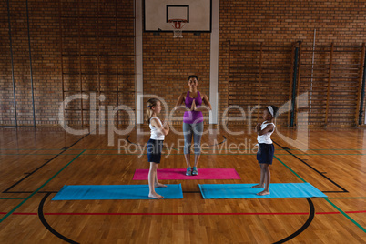 Female yoga teacher teaching yoga to school kids in school