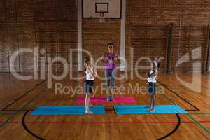 Female yoga teacher teaching yoga to school kids in school