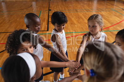 Schoolkids forming hand stack at basketball court