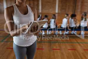 Mid section female basketball coach using digital tablet at basketball court