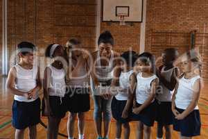 Schoolkids looking their female coach using digital tablet at basketball court