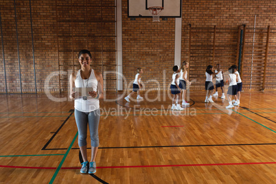 Smiling female basketball coach with digital tablet looking at camera