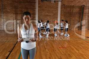 Front view of female basketball coach using digital tablet at basketball court