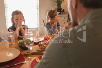 Family praying before having food on dining table