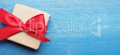 Gift box with a red bow on blue wood